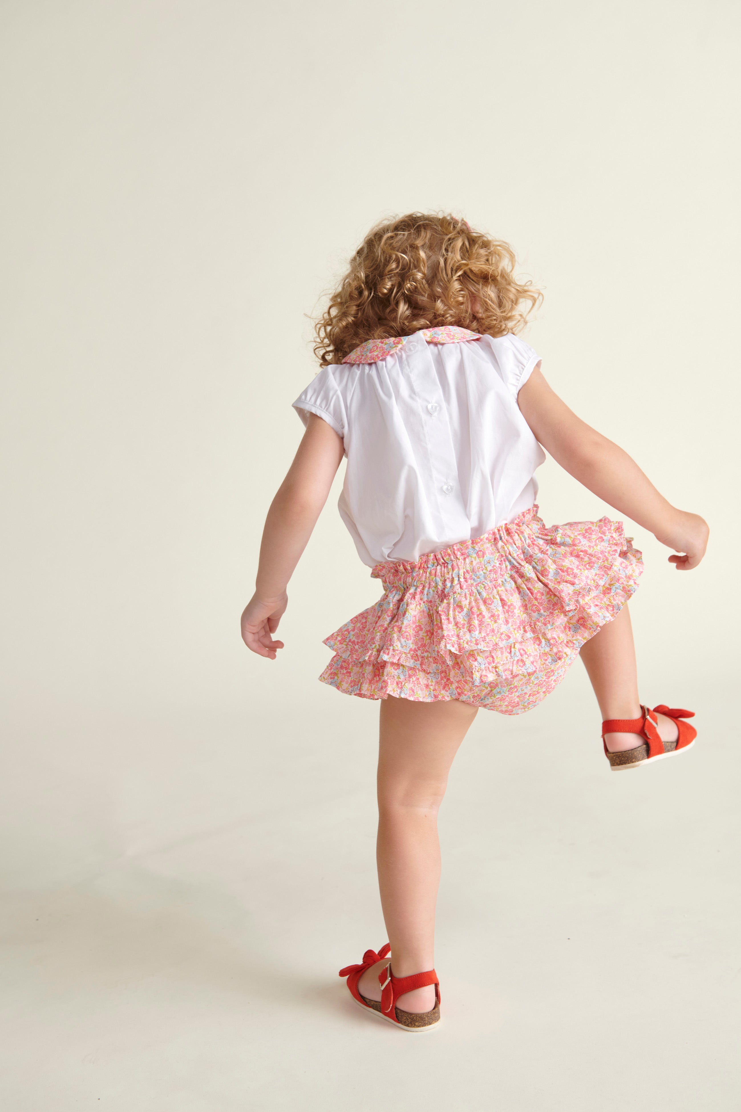 toddler in skort and blouse,  back view
