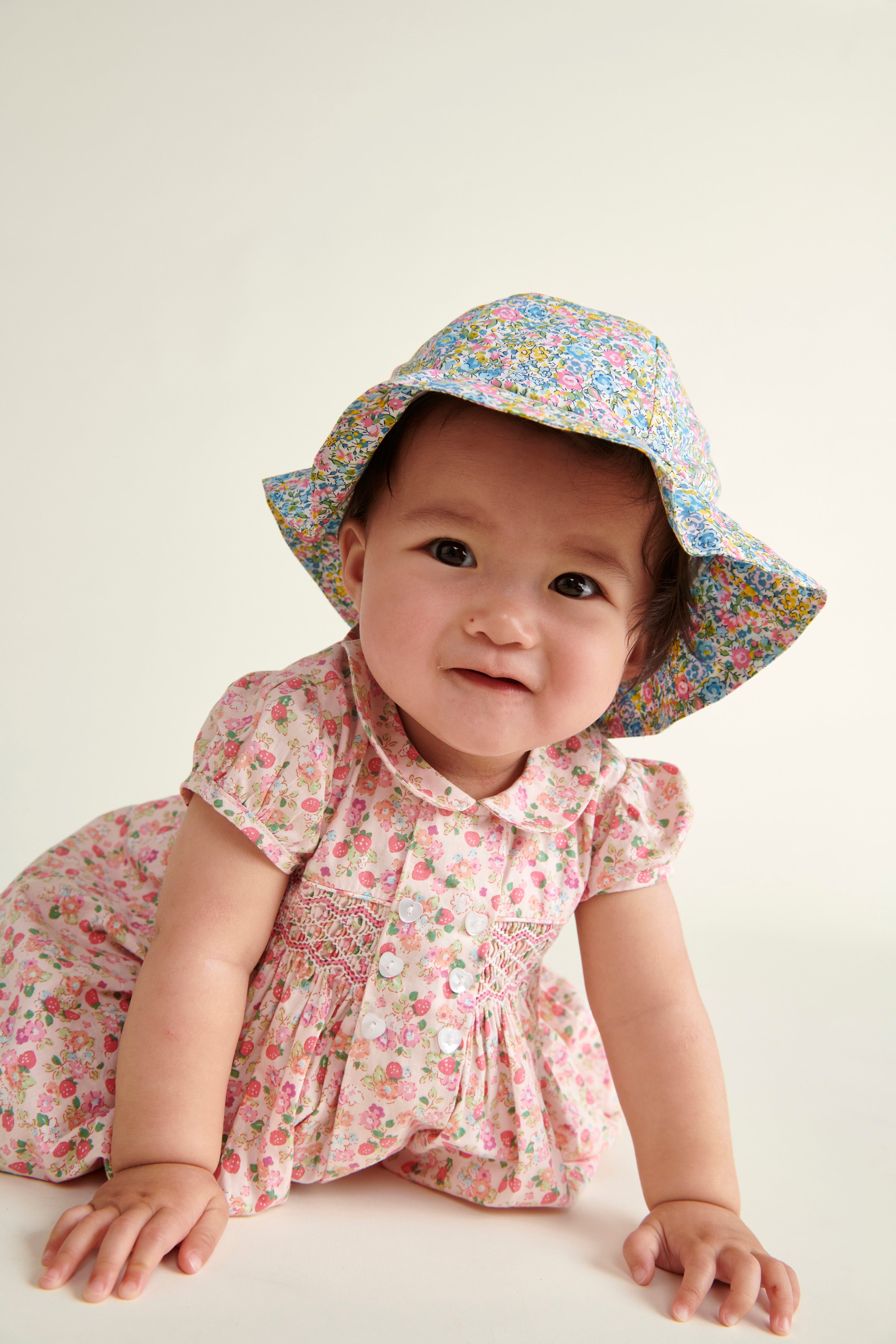 baby in floral sun hat crawling
