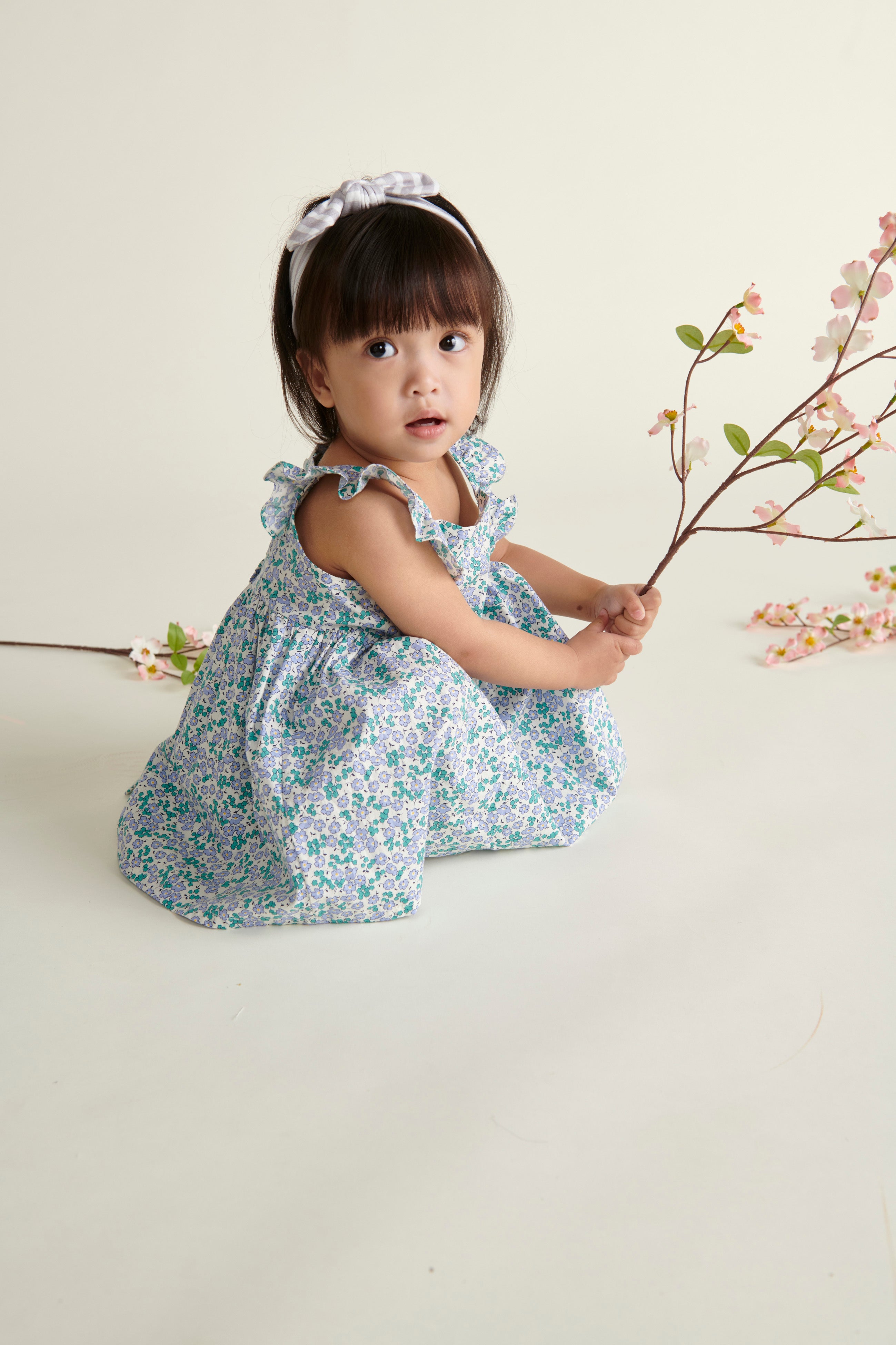 baby in floral sun dress crouching