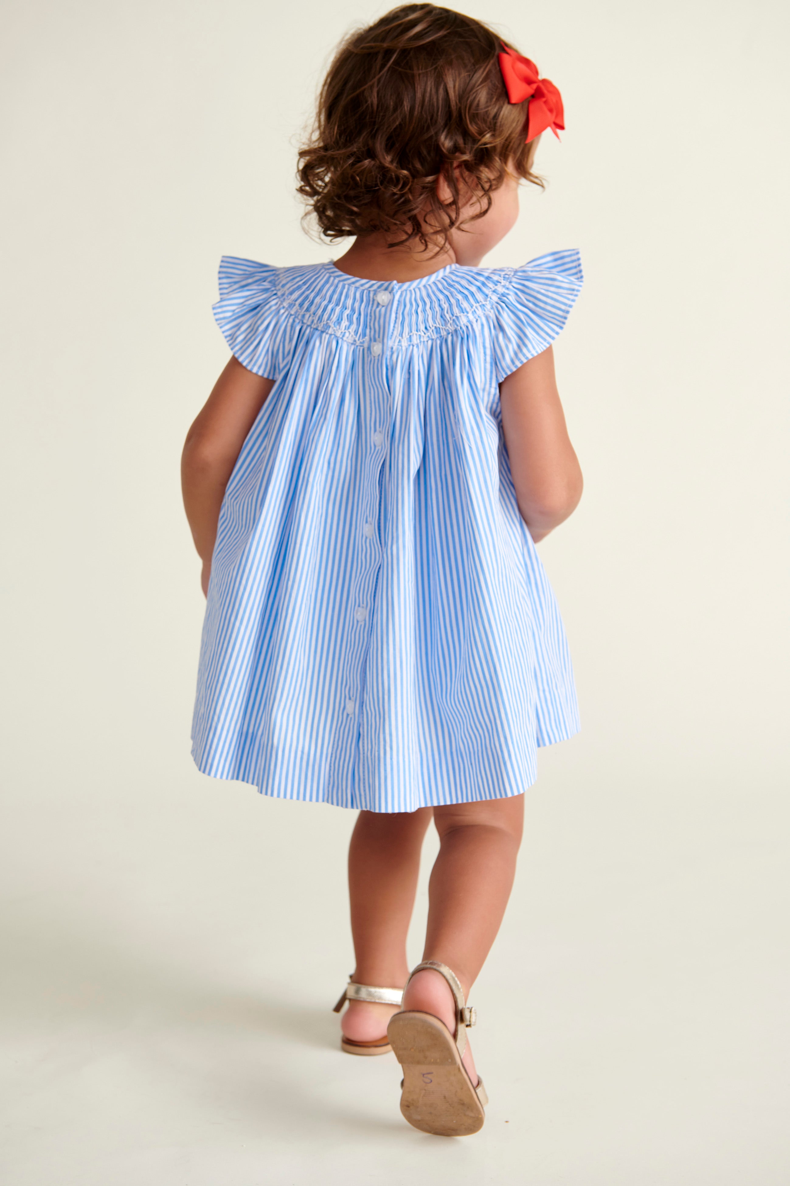 back of  toddler  in pinstripe smocked dress with cherry embroidery