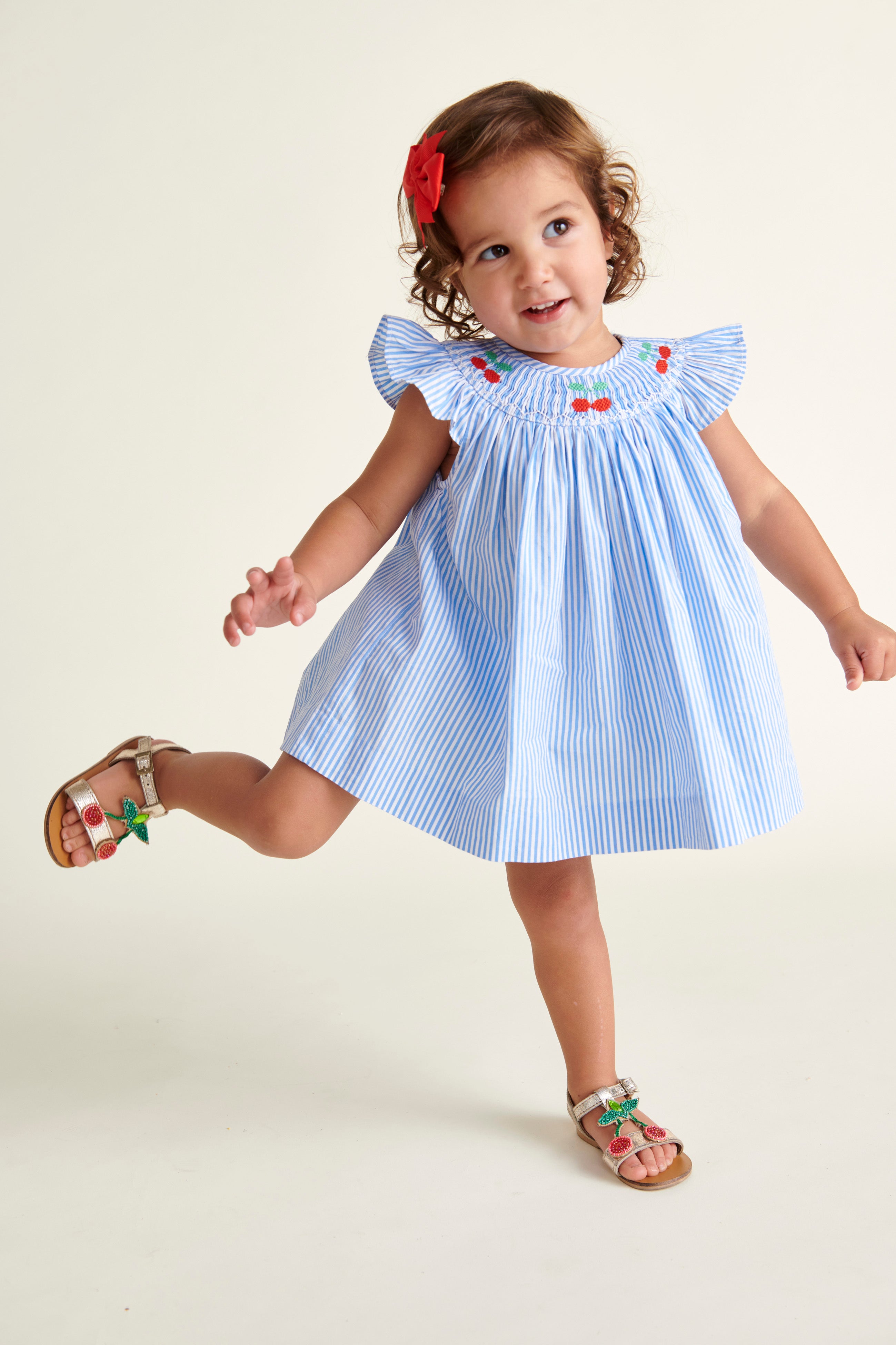 toddler dancing  in pinstripe smocked dress with cherry embroidery