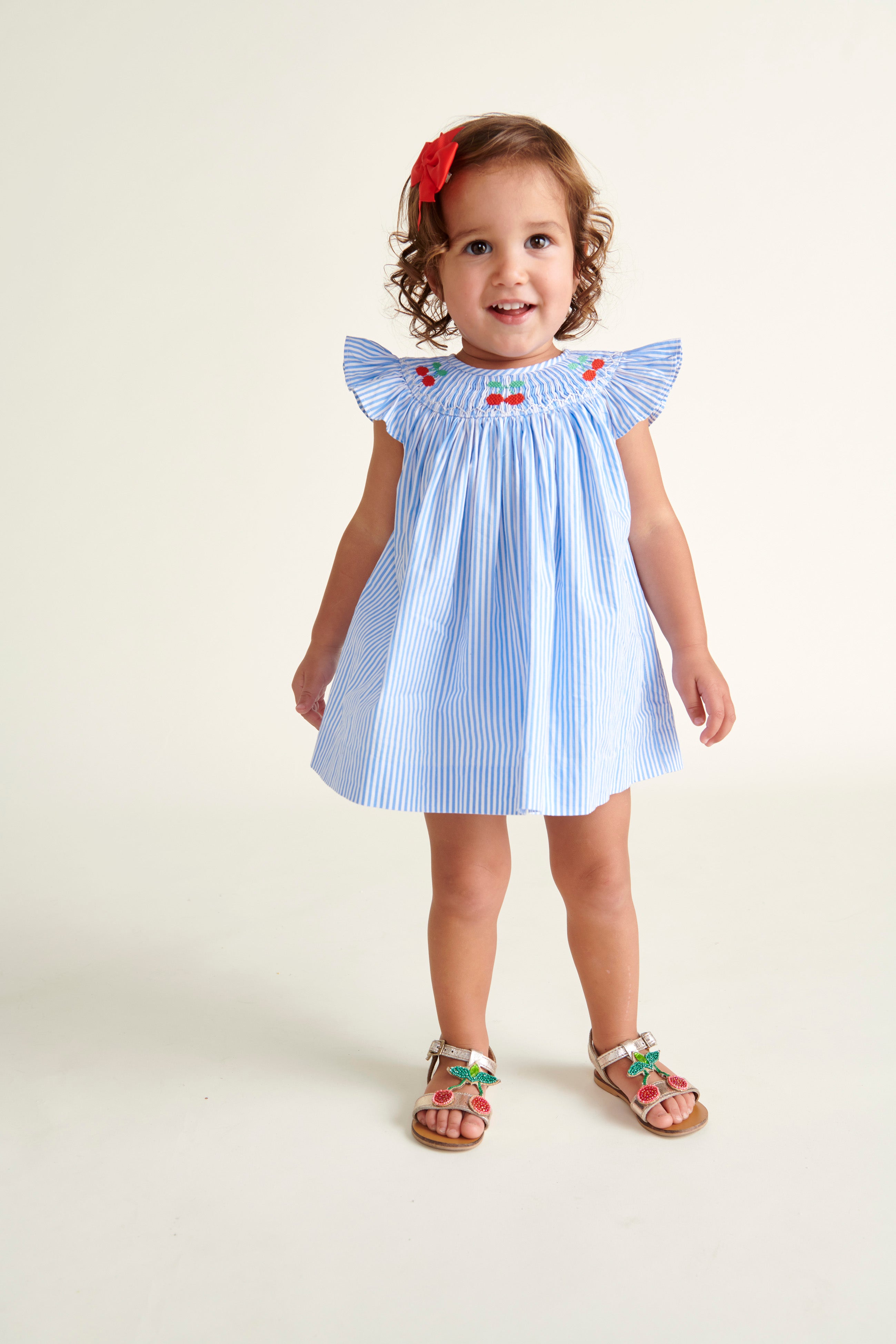 toddler standing  in pinstripe smocked dress with cherry embroidery