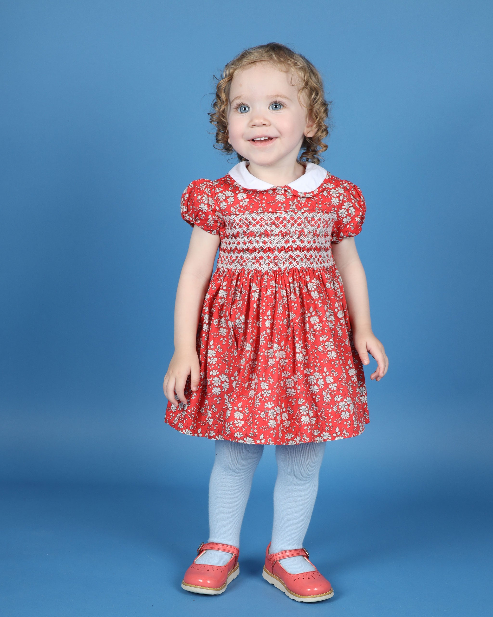 girl in Liberty print smock dress, red and white floral