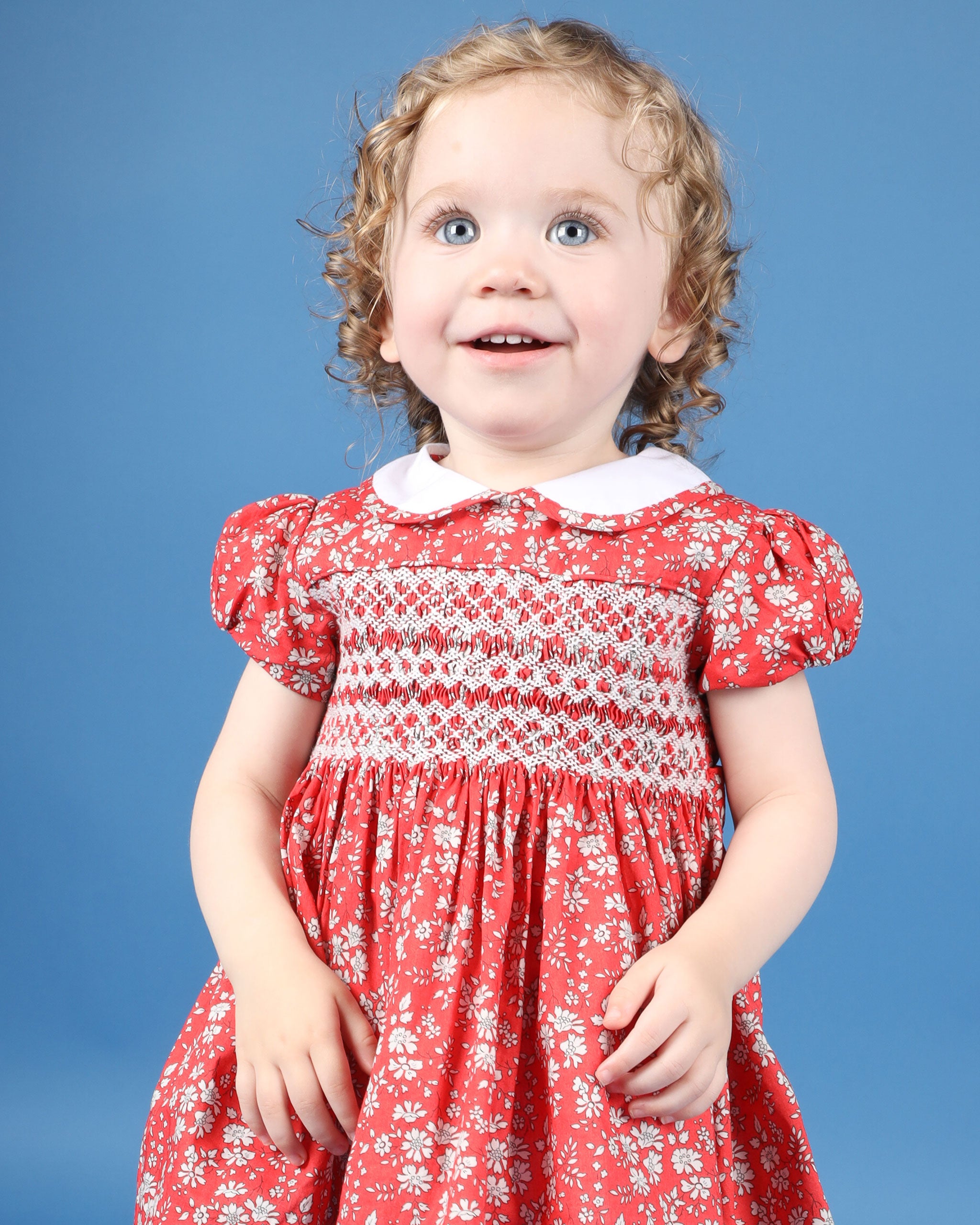 toddler in red and white smocked dress made from Liberty fabric