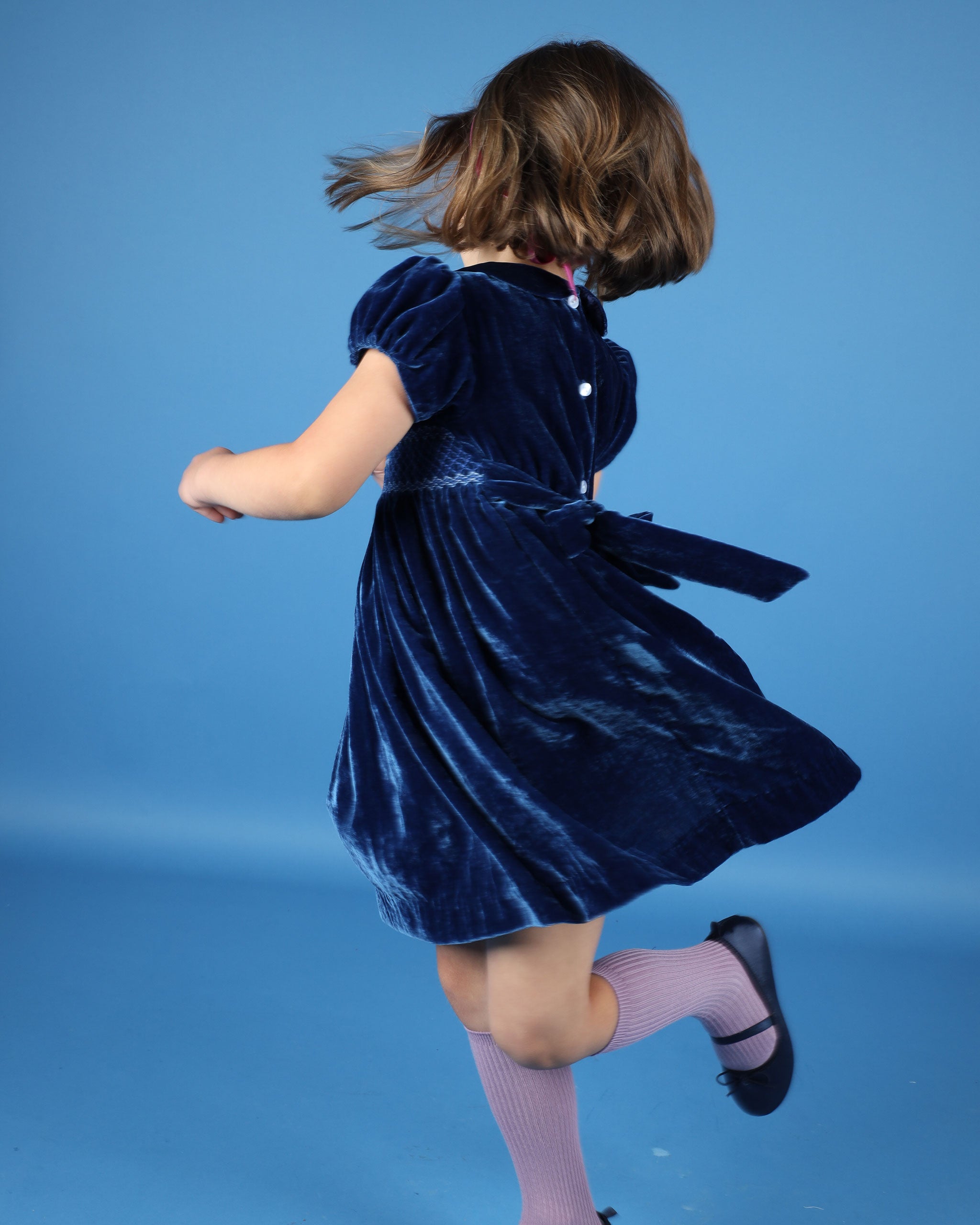 girl twirling in blue velvet dress