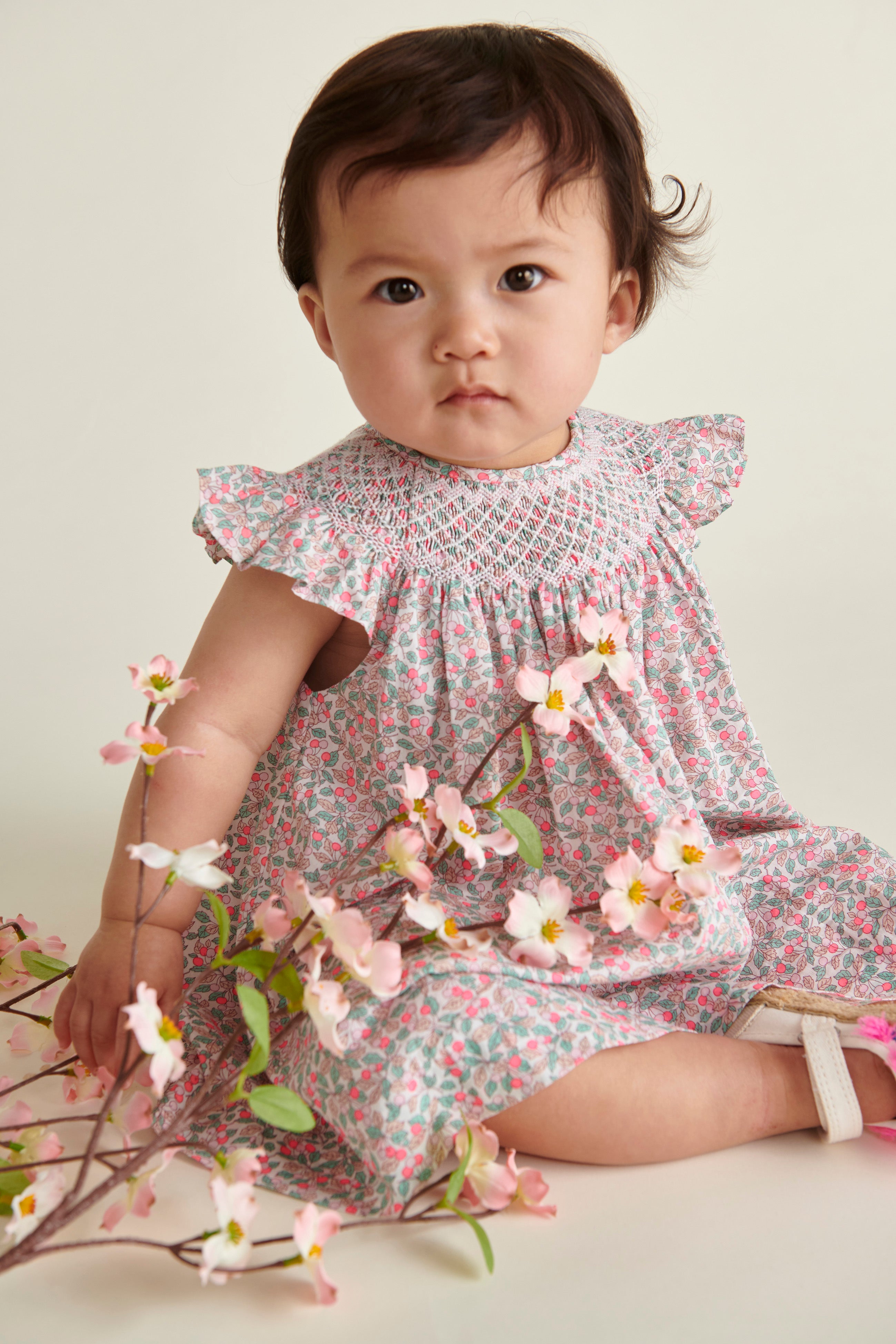 baby model sitting  in hand-smoked Liberty print frill dress, closeup