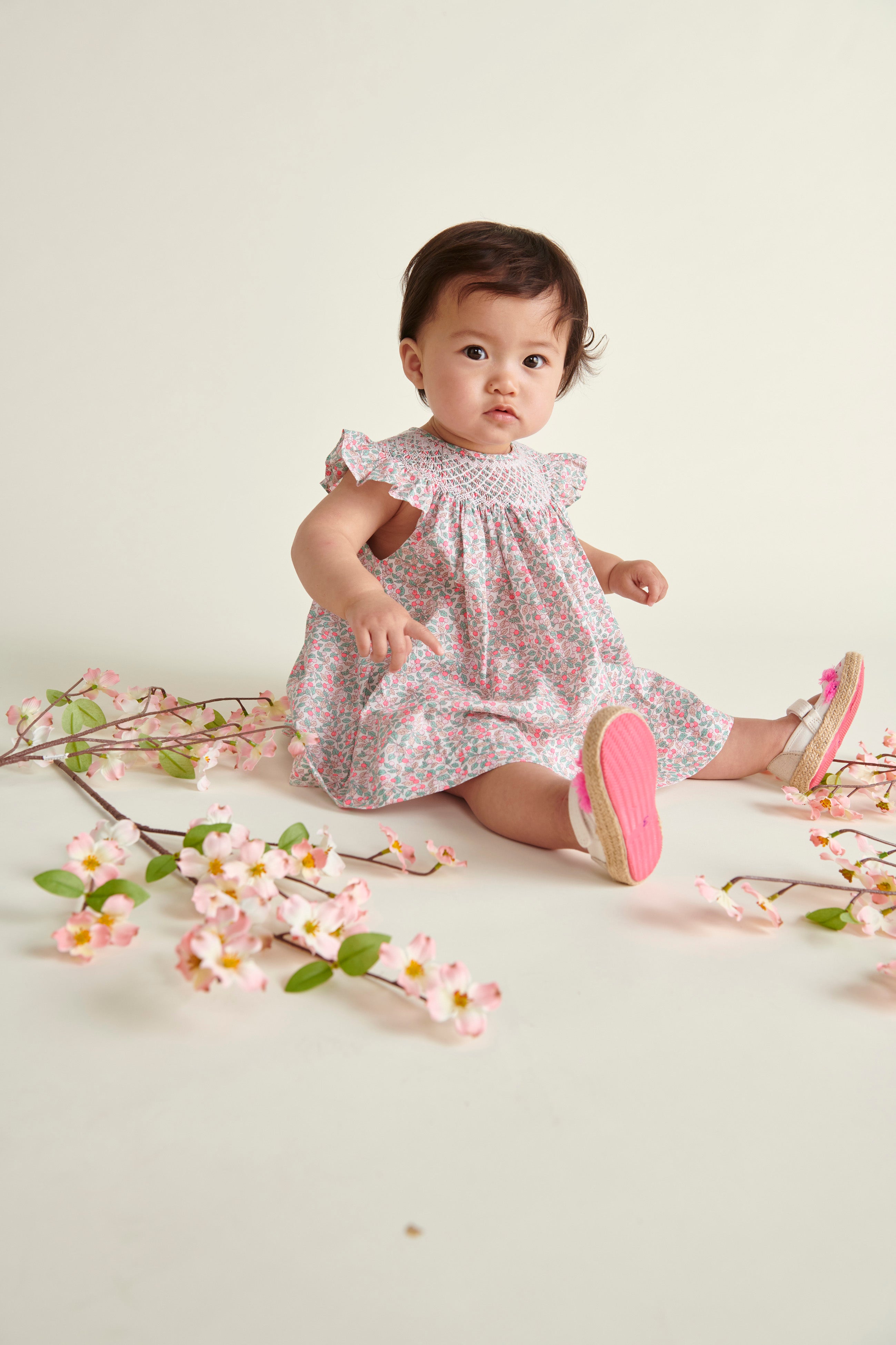 baby model sitting  in hand-smoked Liberty print frill dress 