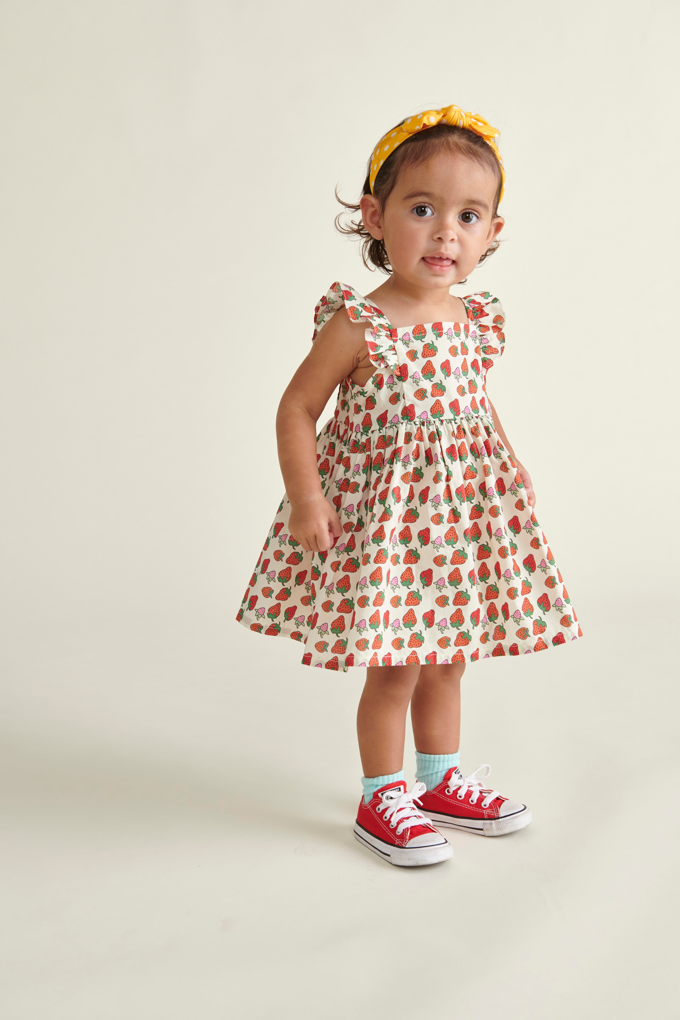 toddler girl i n Strawberry sun dress, standing