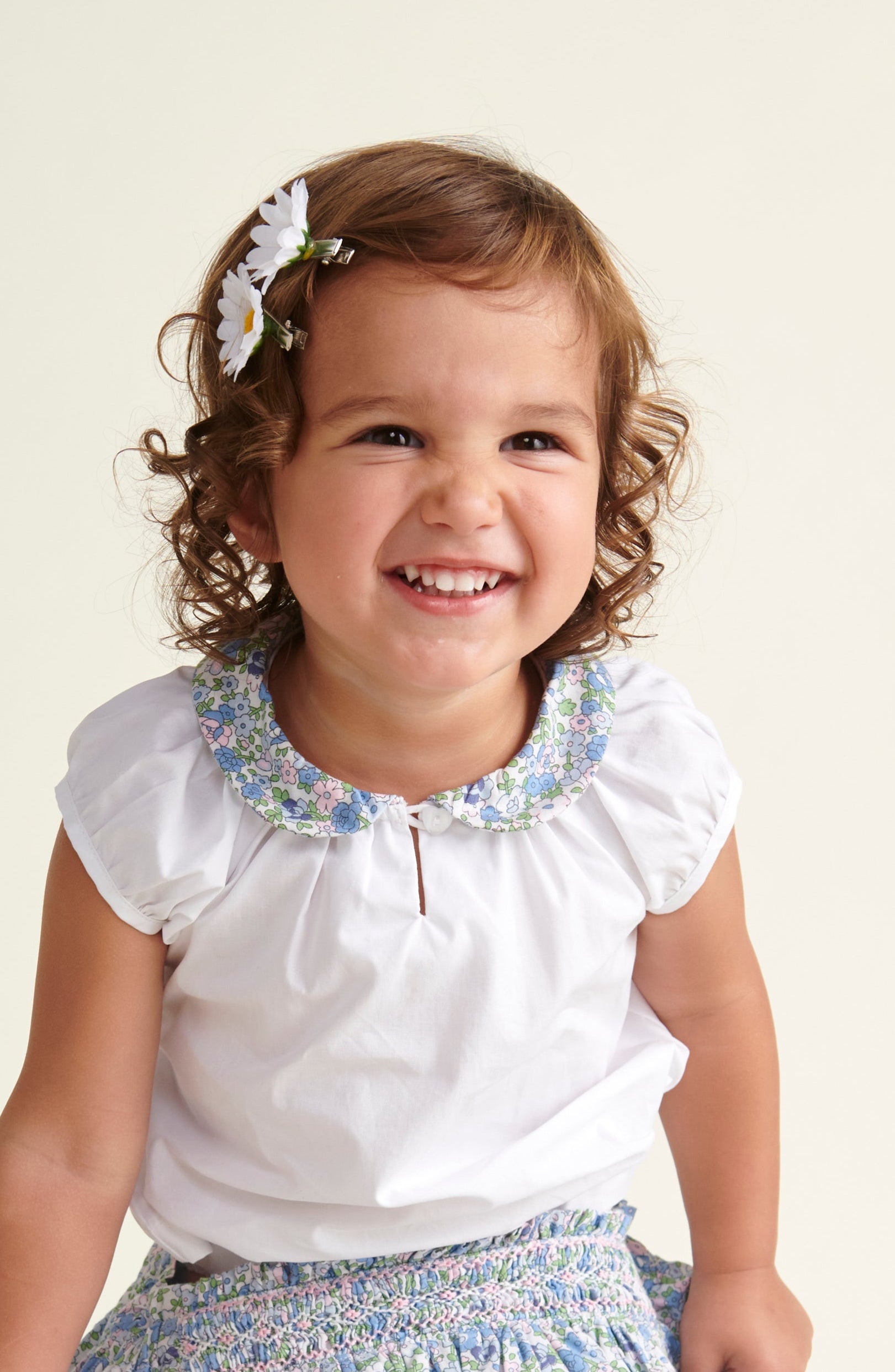 toddler smiling in white blouse with floral collar