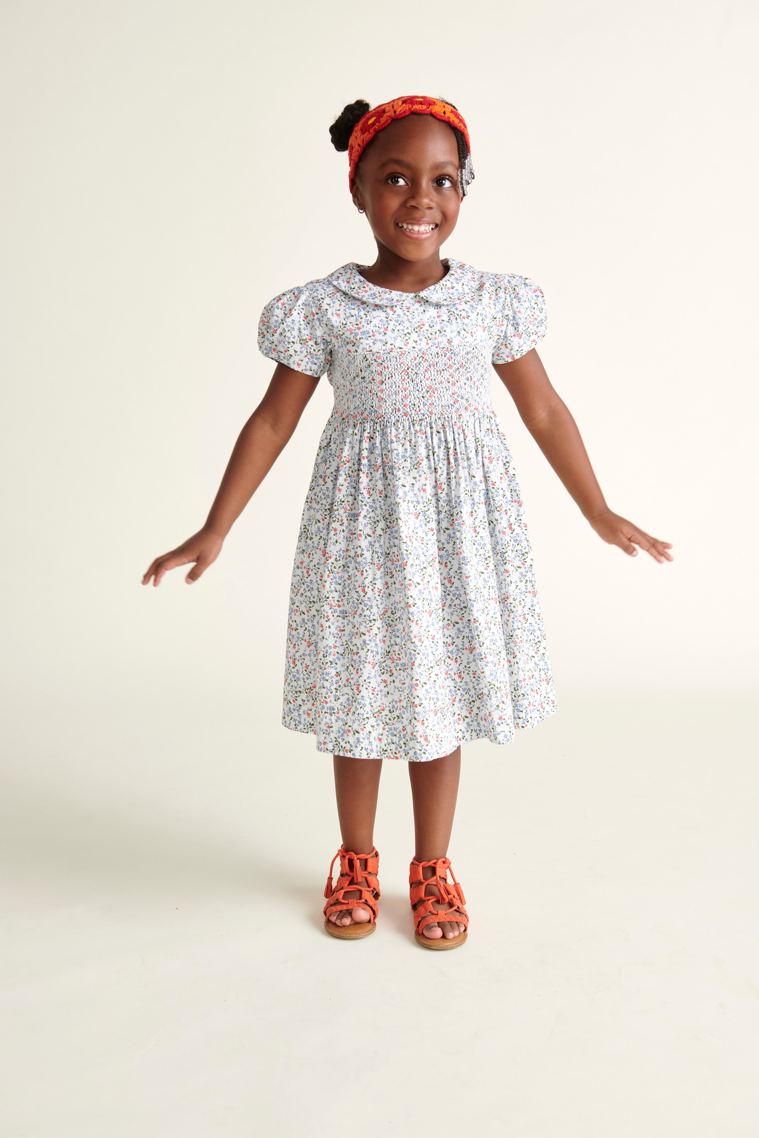 girl standing and wearing a  ditsy floral white smoked dress