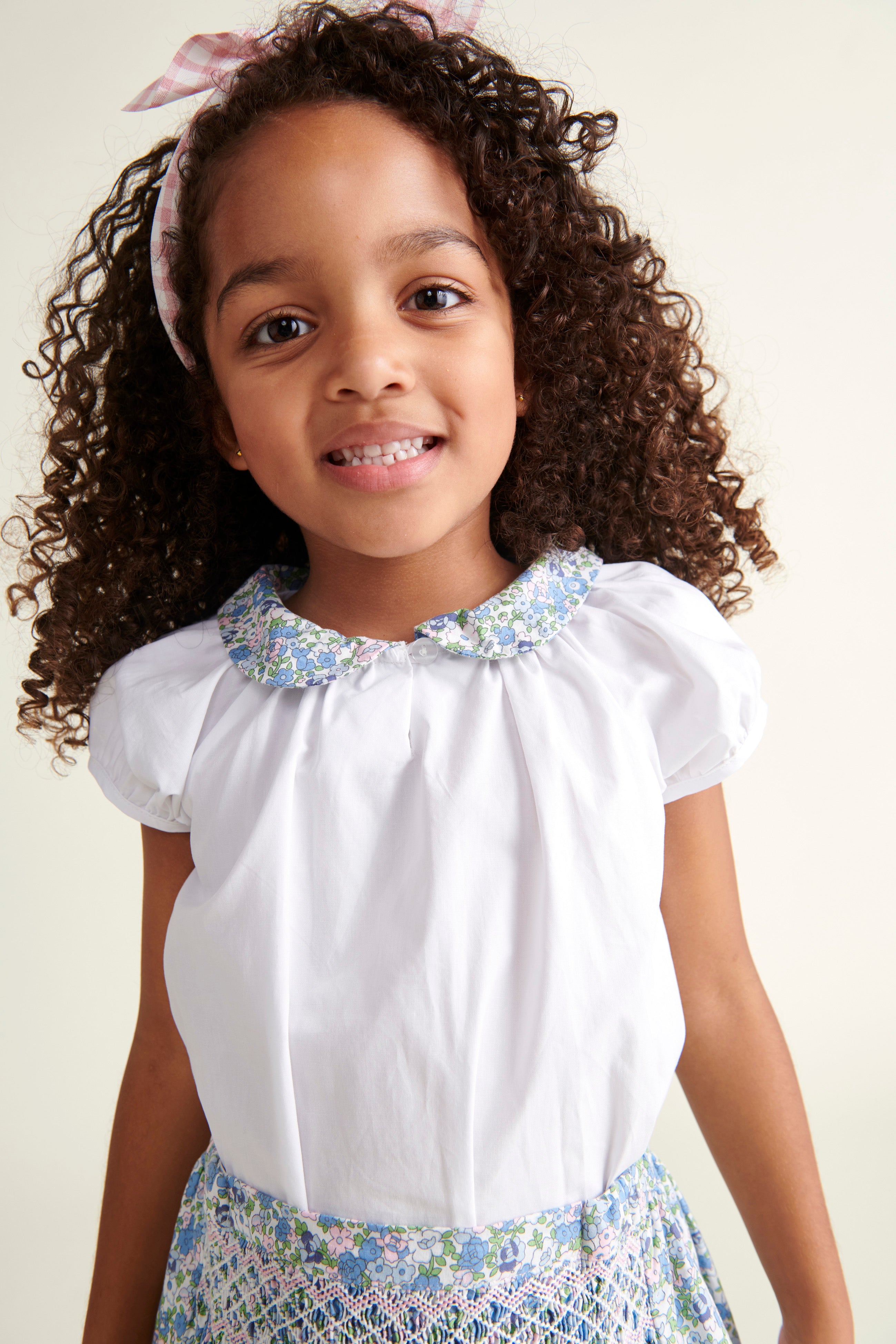 girl in white blouse with floral collar, also wearing matching skirt