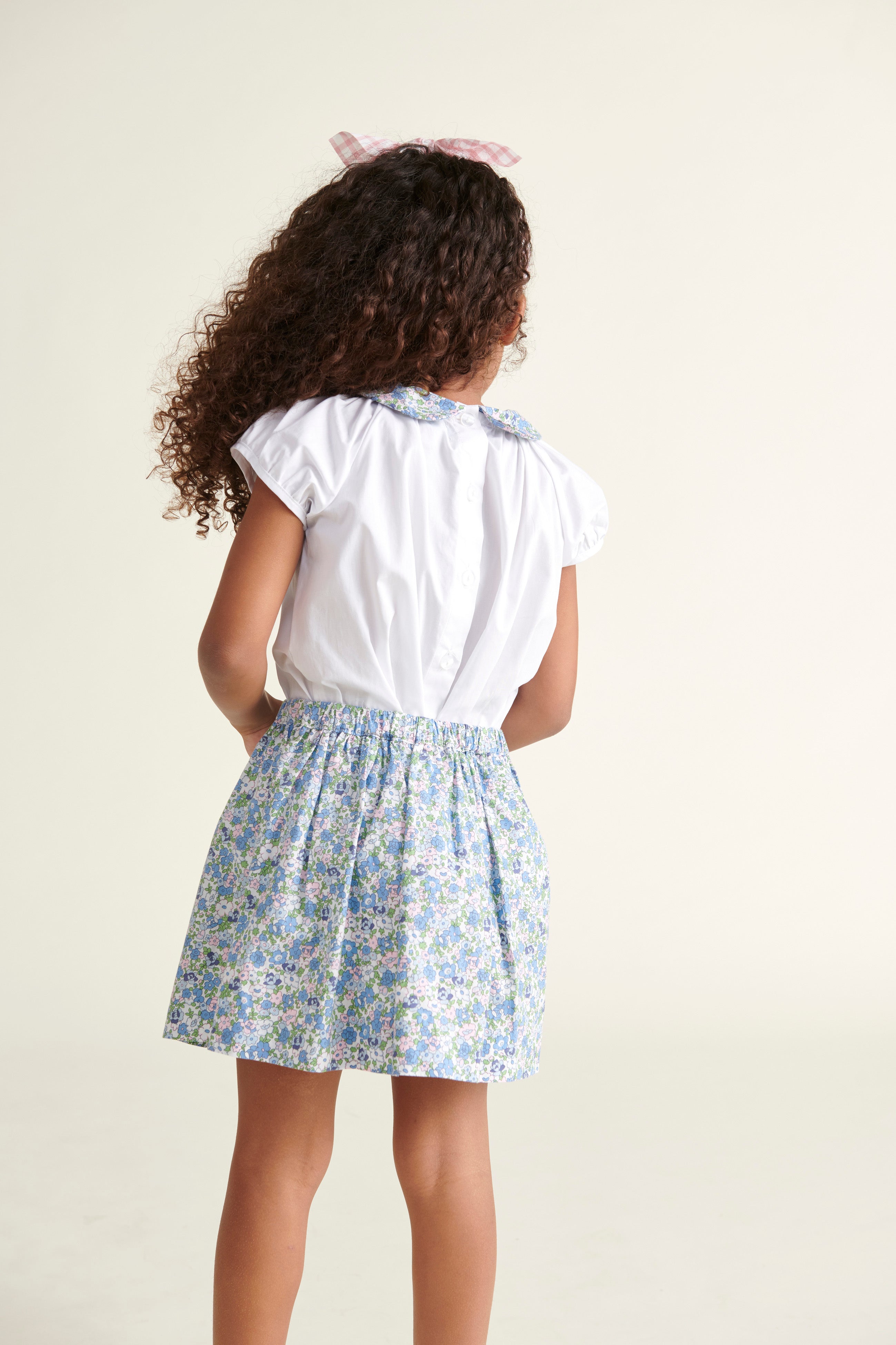 girl in white blouse with floral collar from behind