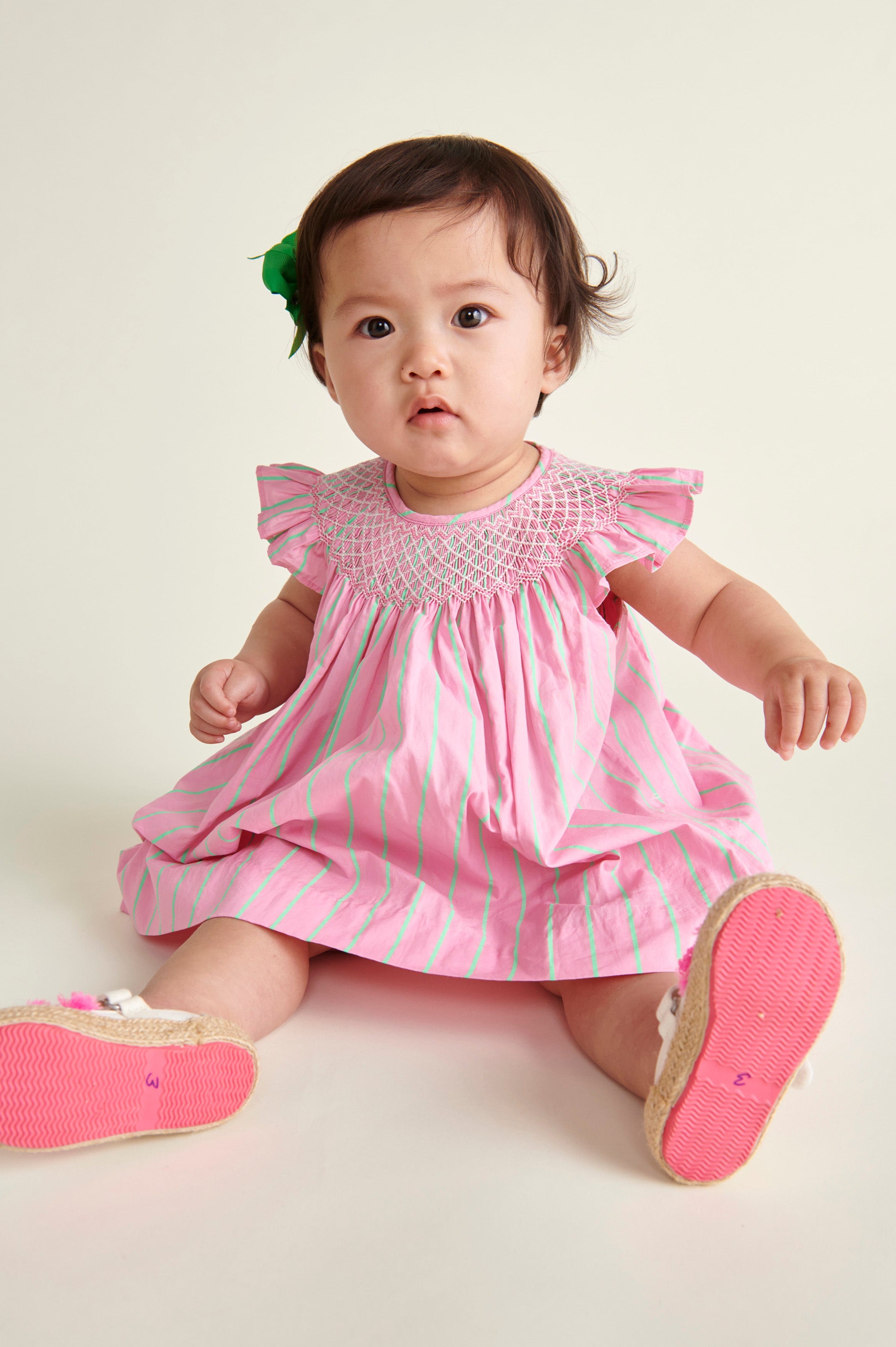 baby in pink  and neon green pinstripe smocked dress, sitting