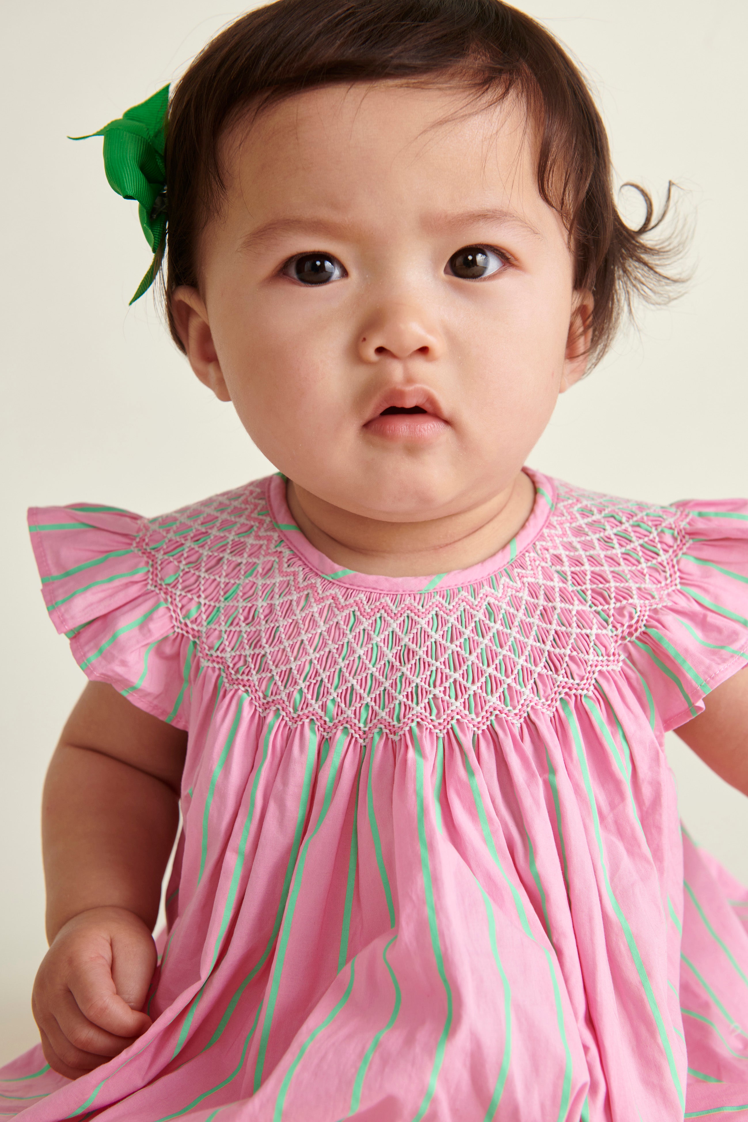 baby in pink  and neon green pinstripe smocked dress, closeup