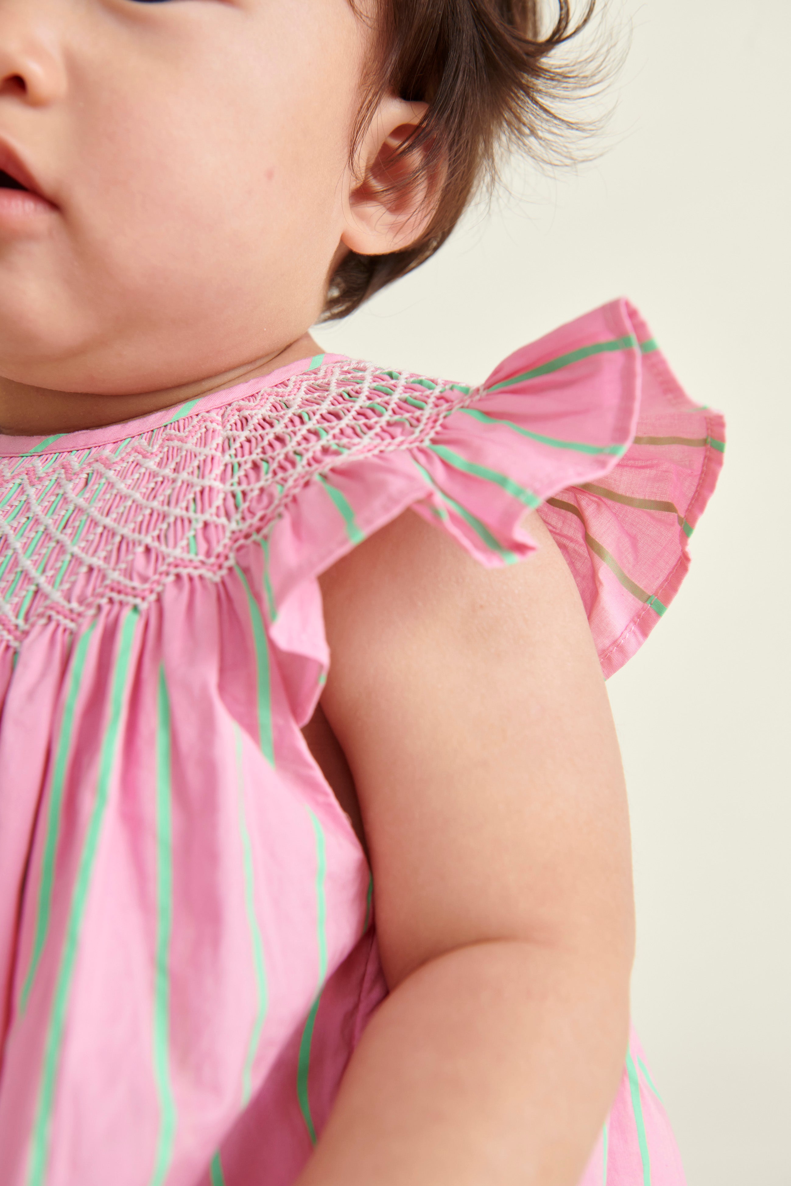 baby in pink  and neon green pinstripe smocked dress, detail