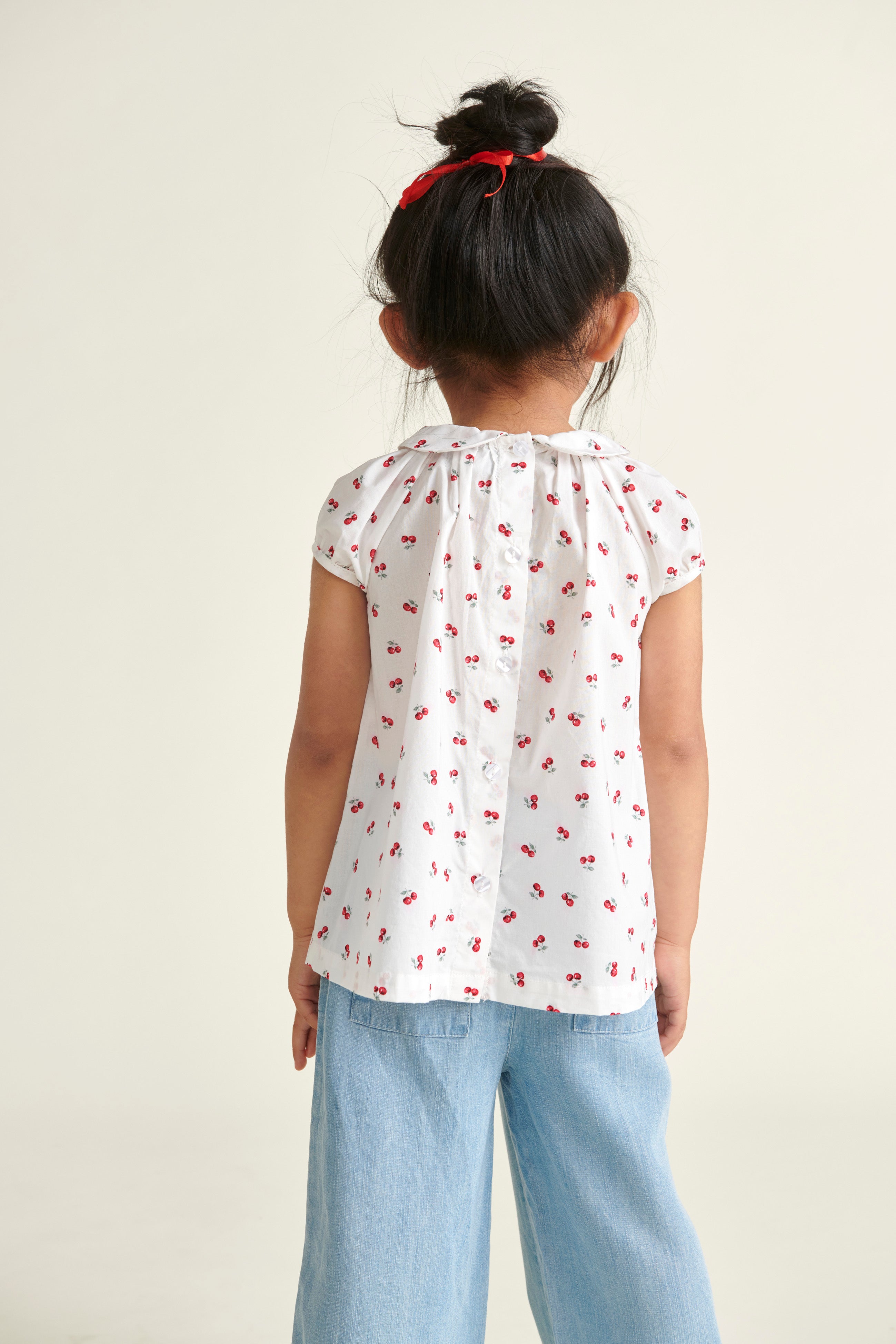 girl in cherry print blouse, back view 