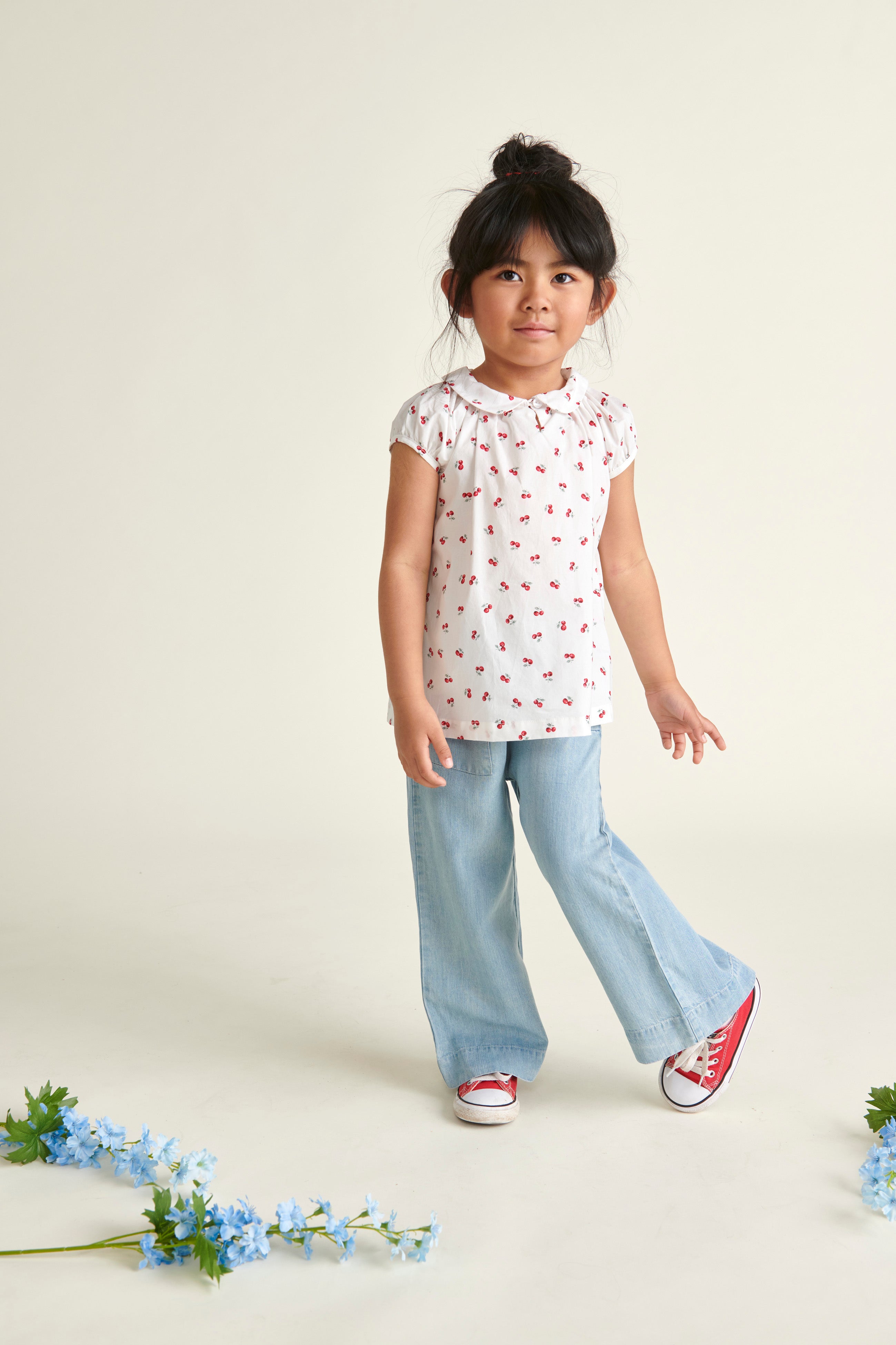 girl in cherry print blouse and jeans posing