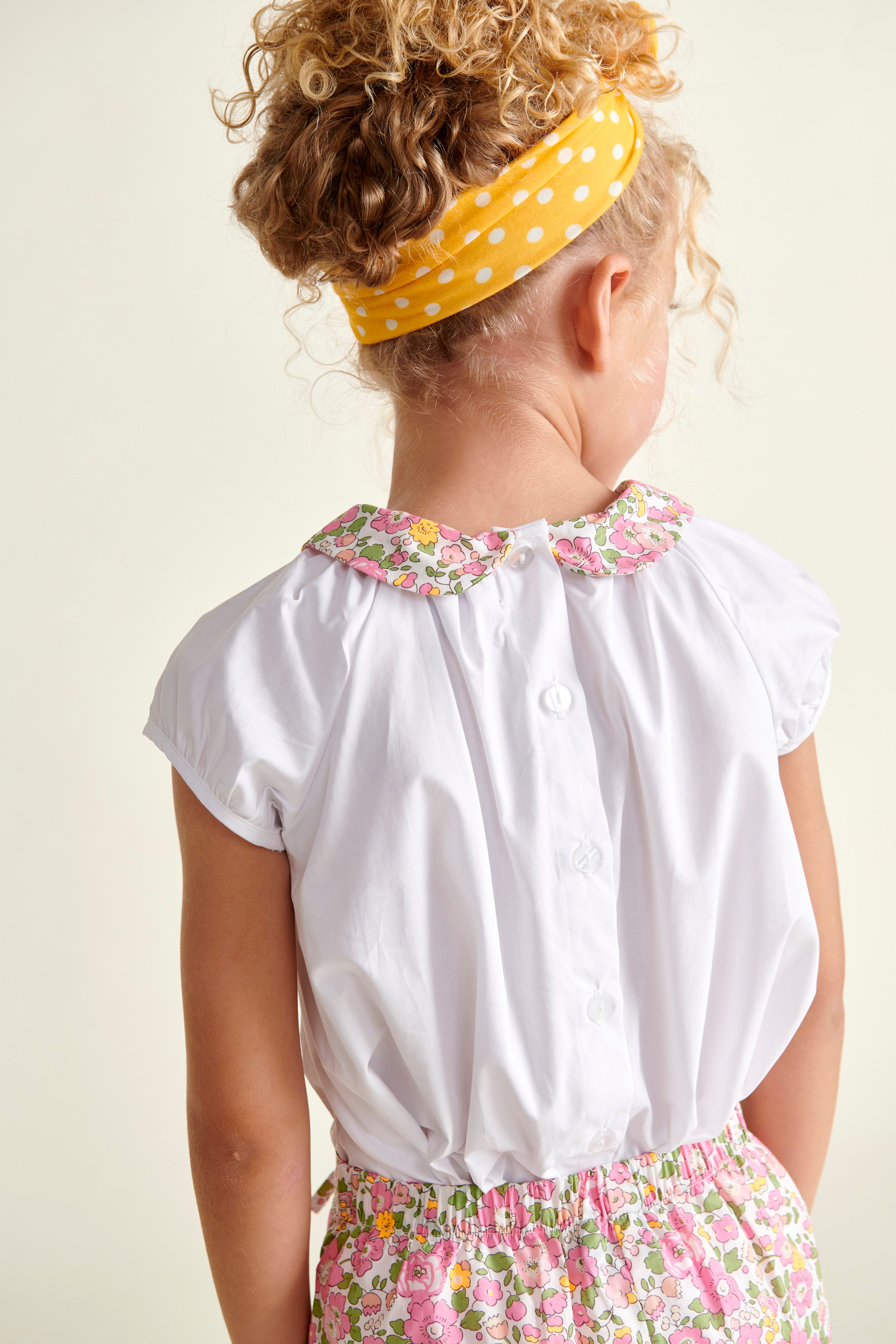 girl in blouse with floral collar, back view