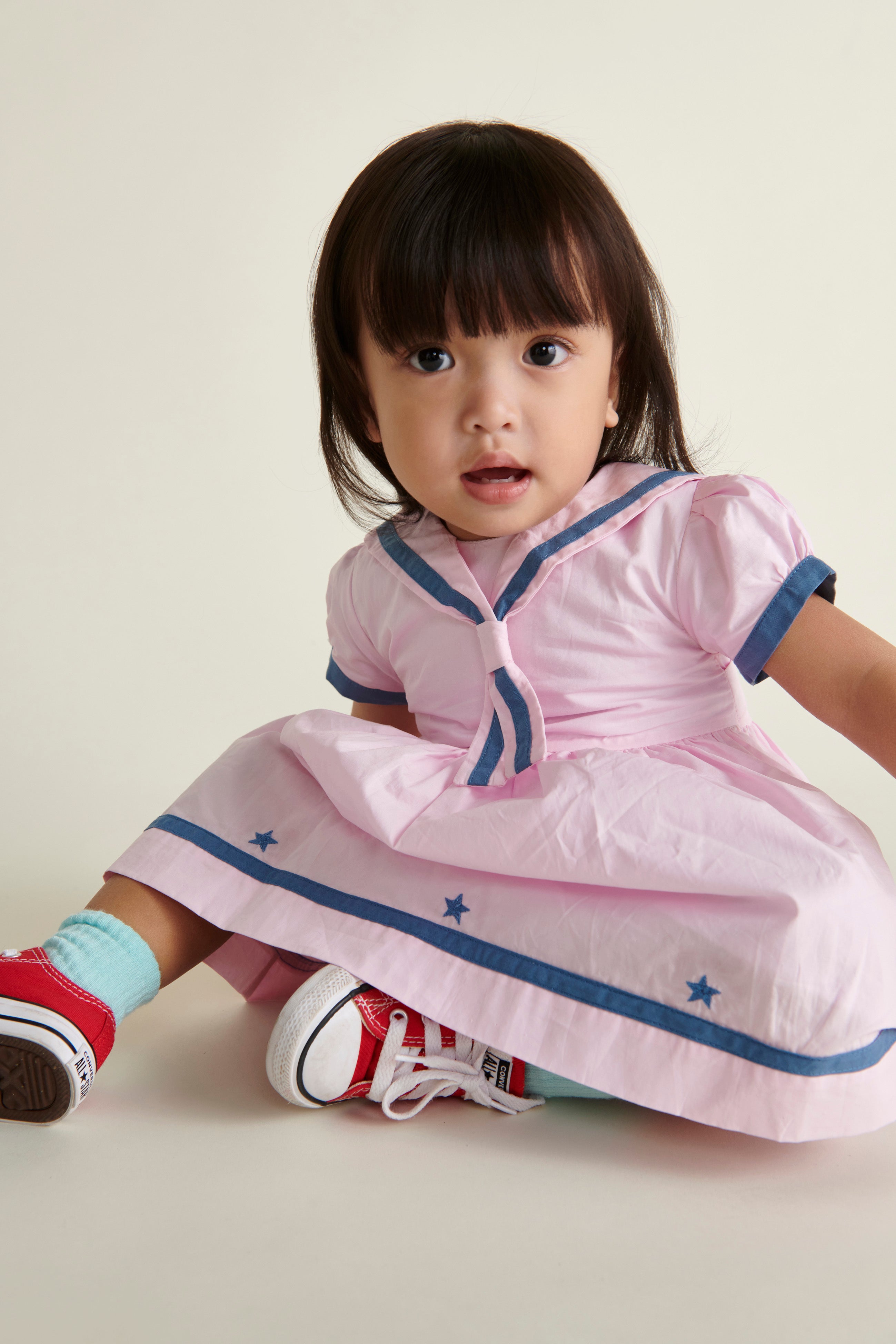 toddler girl in pink and navy sailor dress, sitting