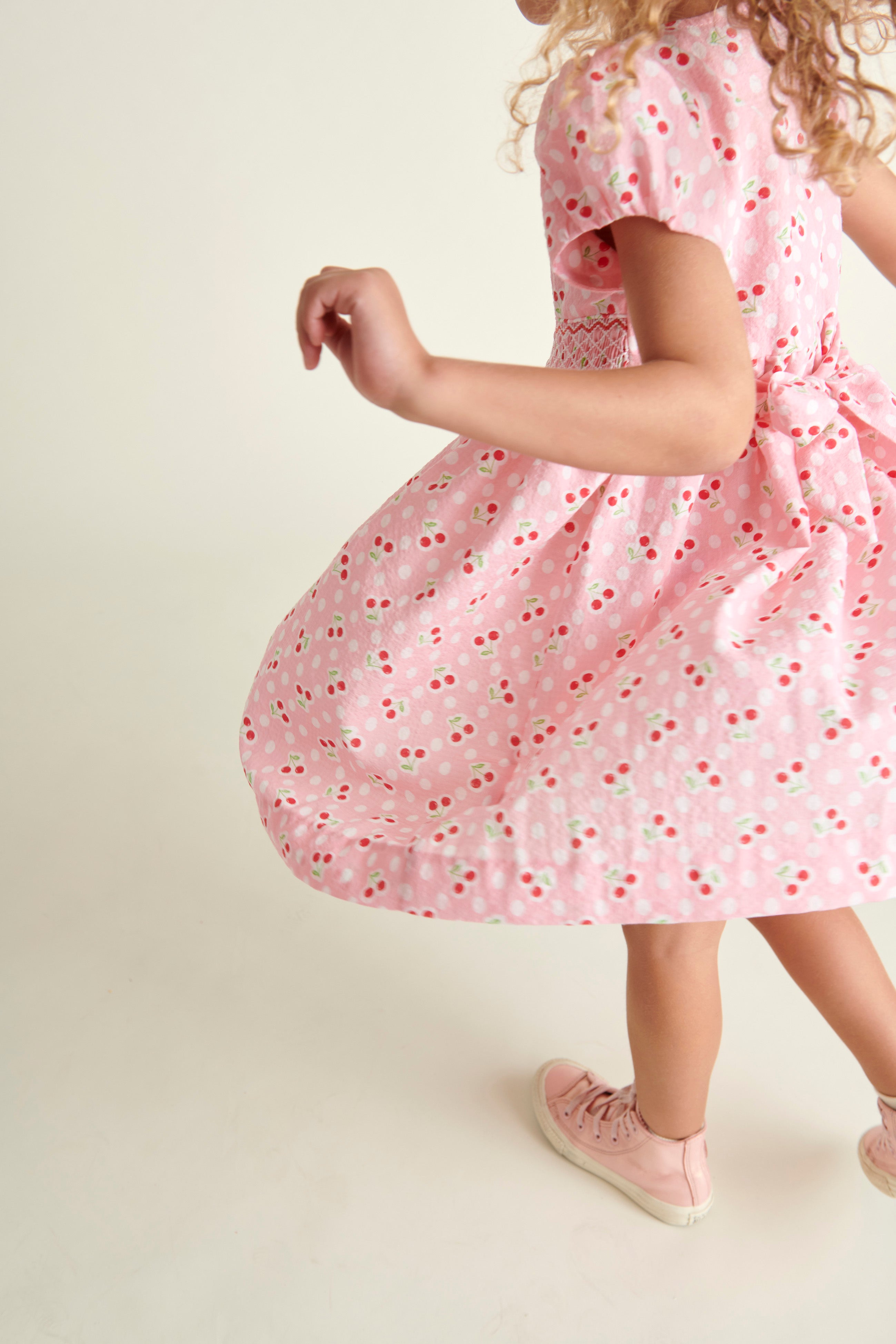 girl in pink cherry print dress, twirling