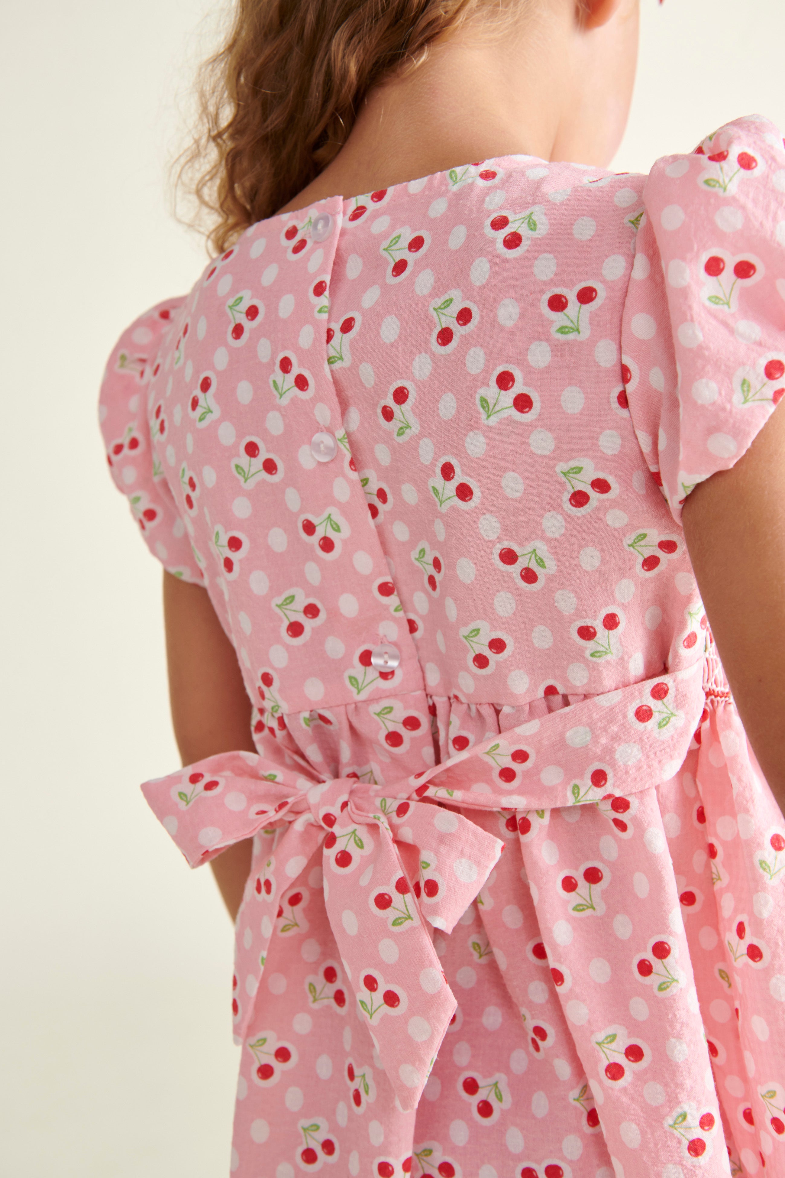 girl in pink cherry print dress, back view