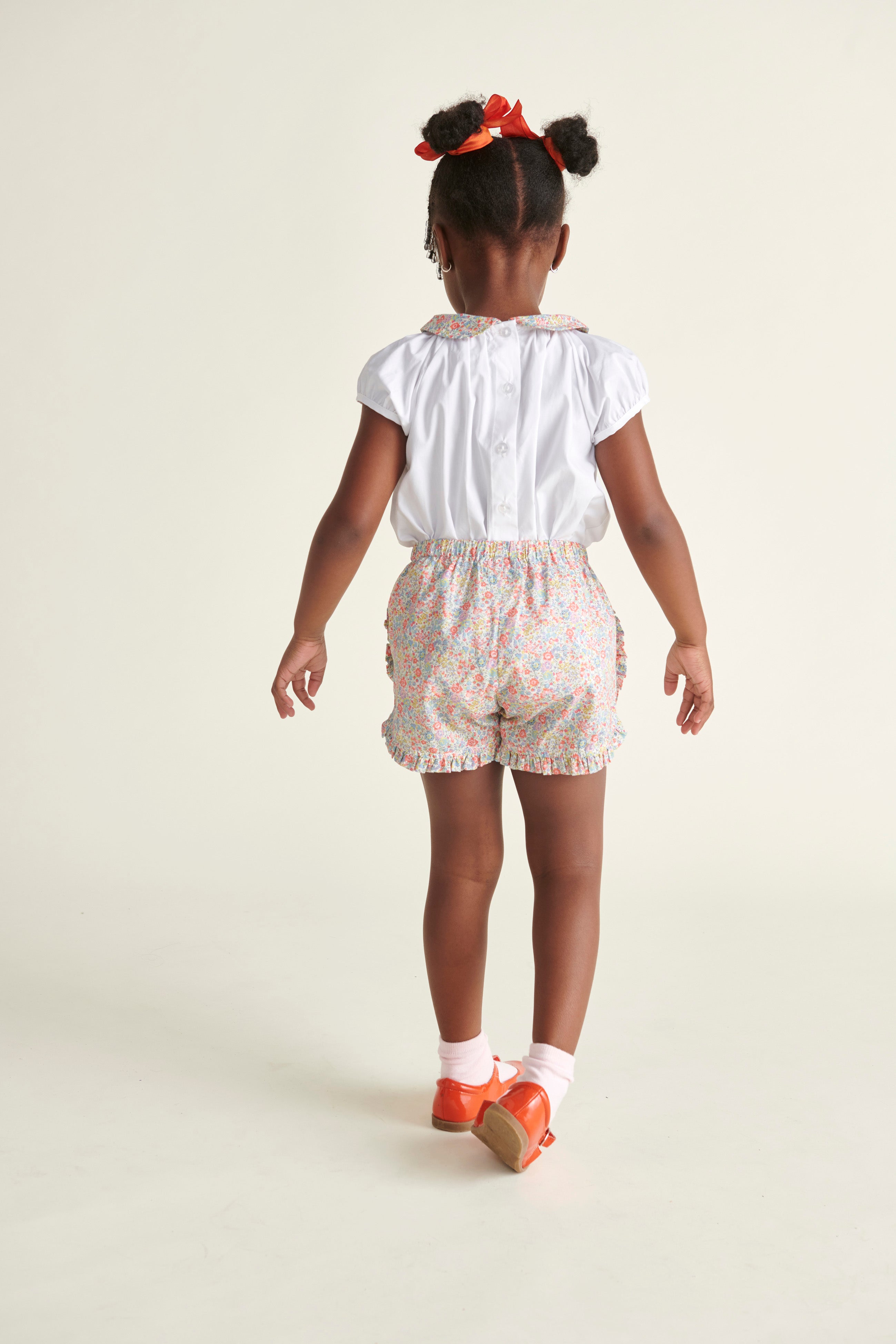 girl in blouse and shorts, back view