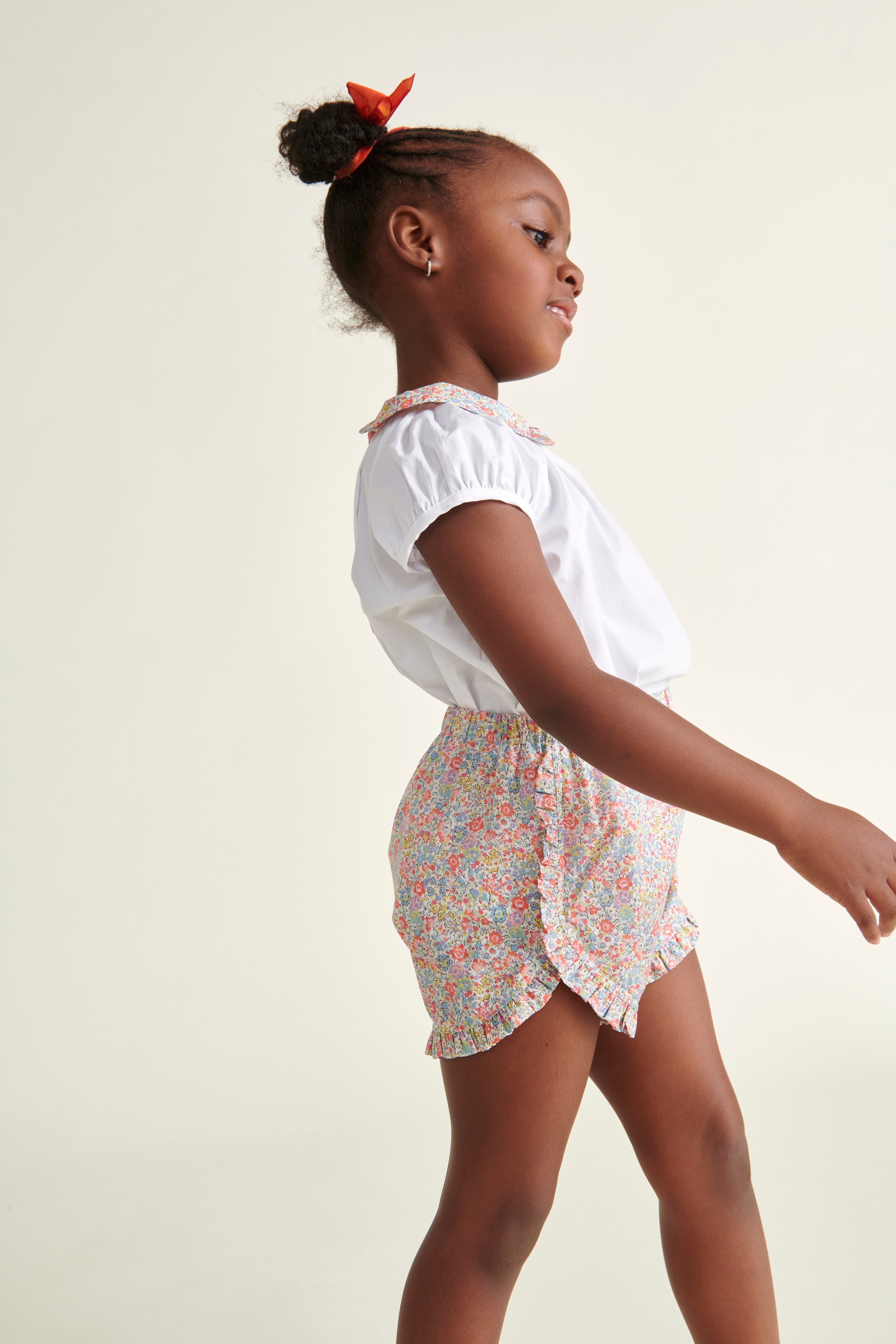 girl in shorts, floral and matching white blouse with floral collar 