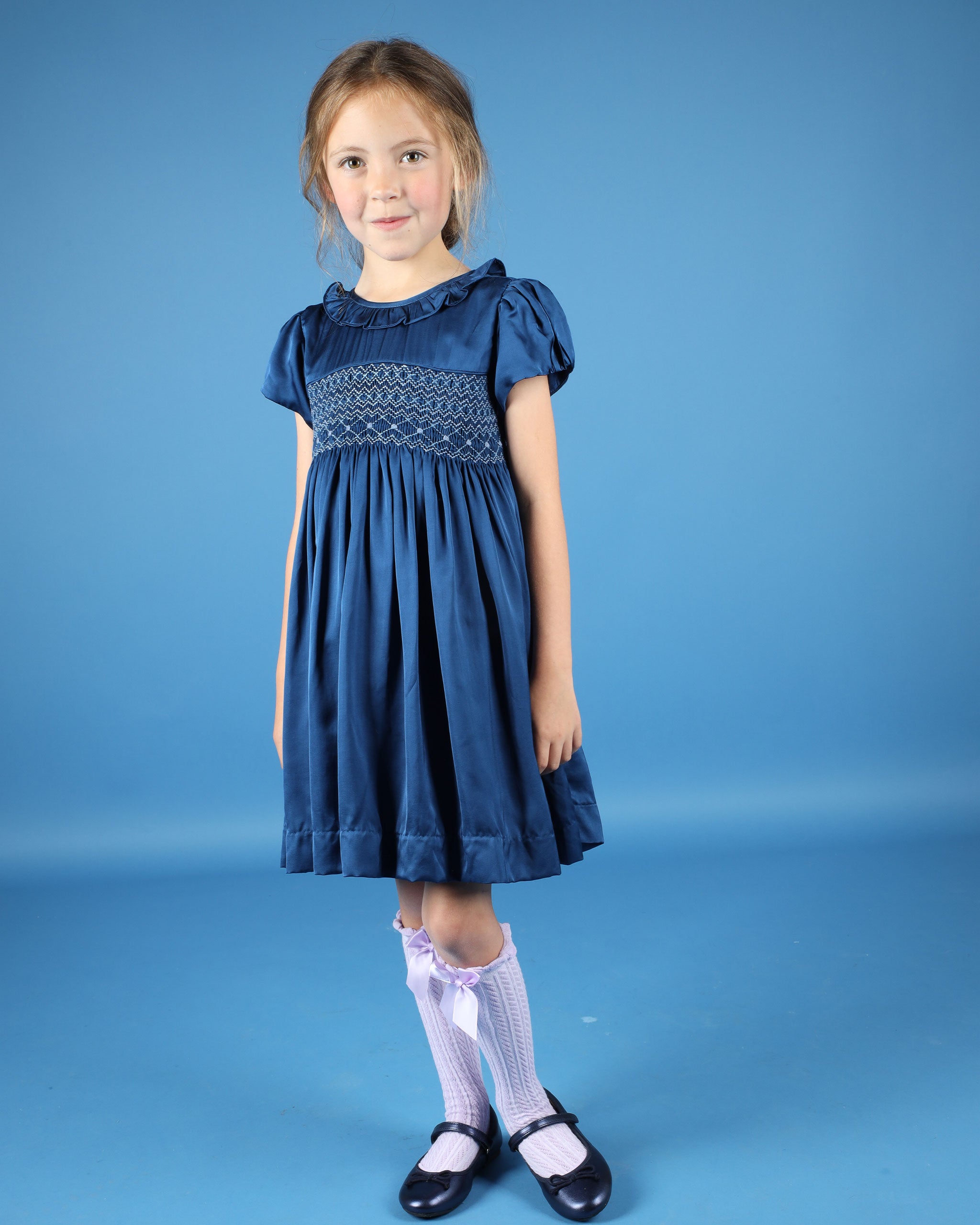 girl in navy satin party dress with smocking 