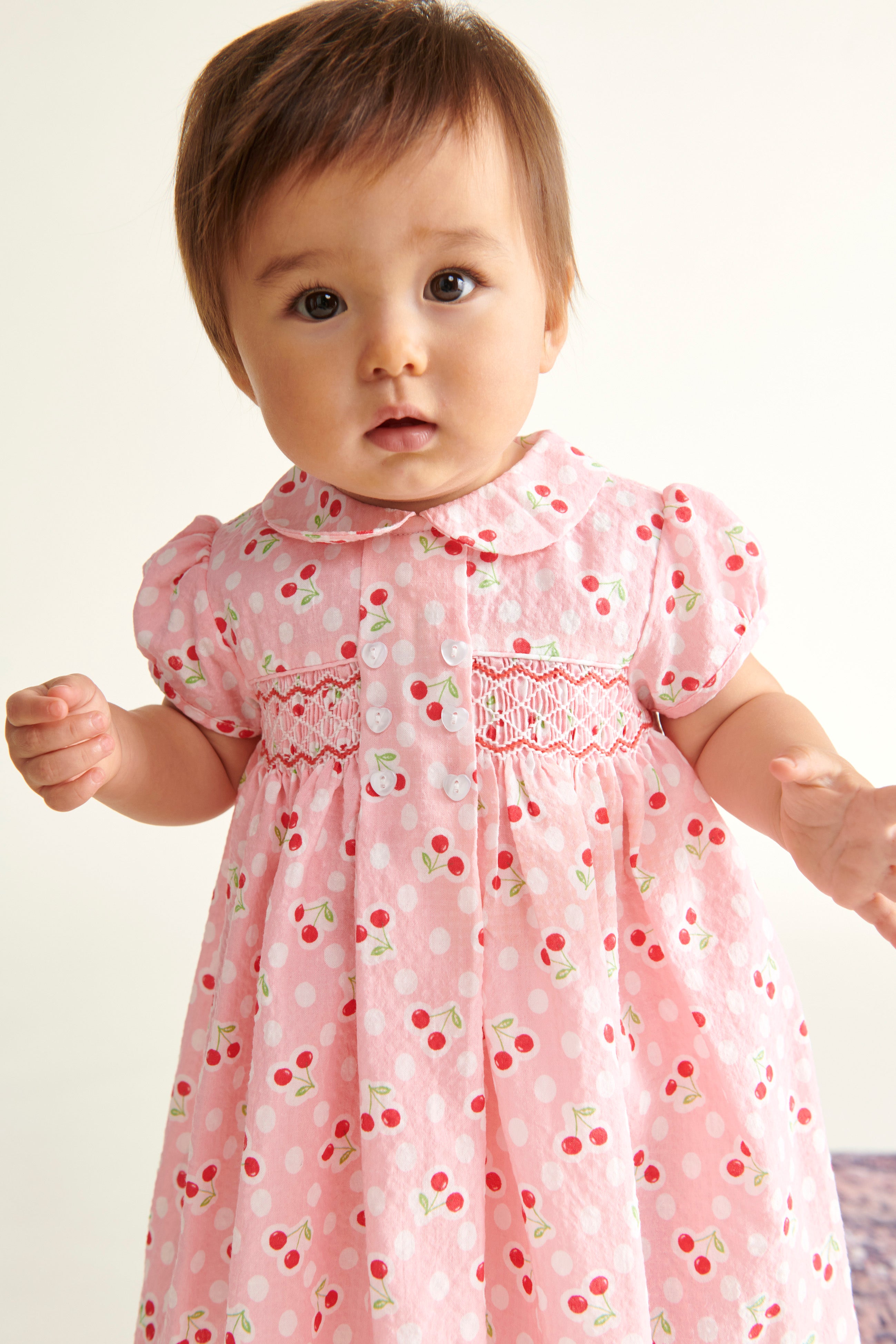 baby in pink smock dress