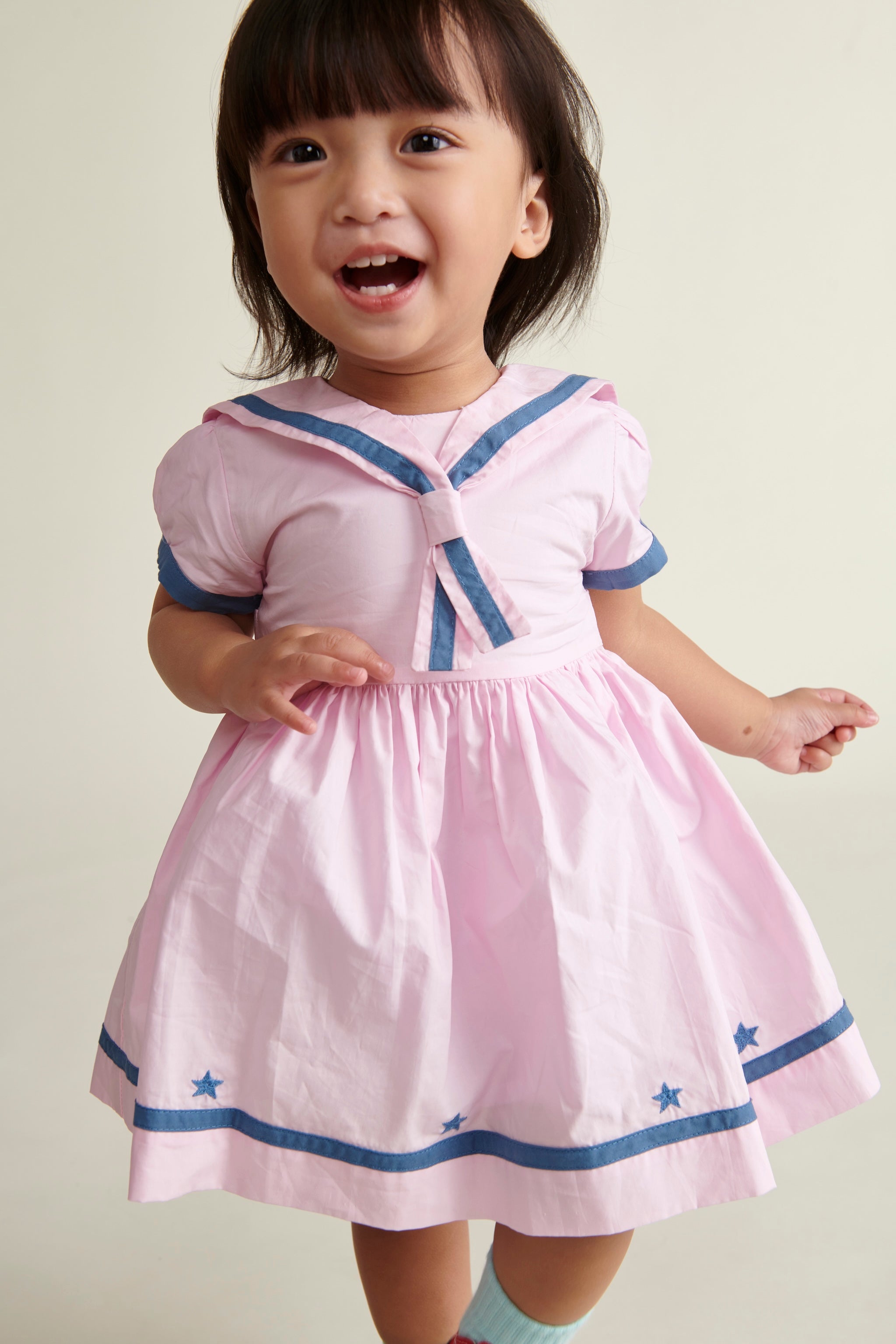 toddler girl smiling in pink and navy sailor dress